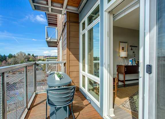 A balcony with a table and chairs overlooking a parking lot.