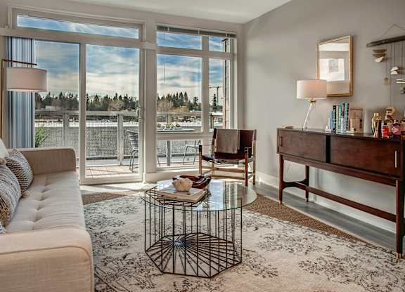 A living room with a couch, a coffee table, and a large window.