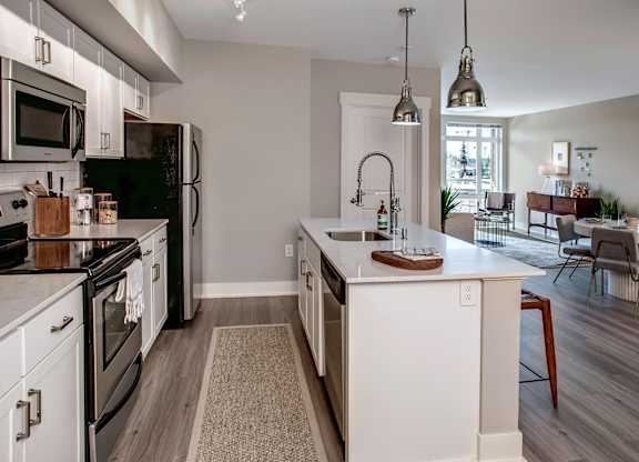 A kitchen with black and white appliances and wooden floors.