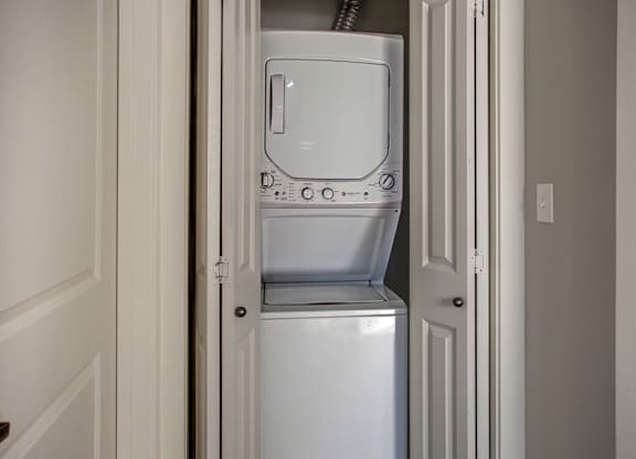 A white dishwasher is in a narrow space between two doors.