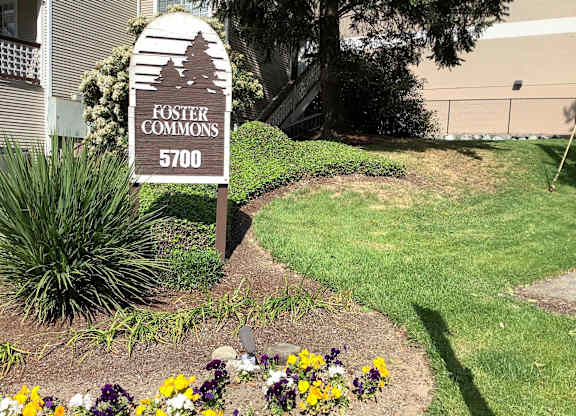 A sign for Foster Commons 5700 stands in a flower bed.