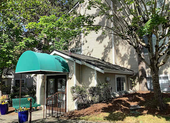 A house with a green awning and a tree in front.