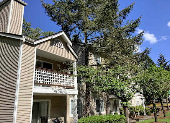 A house with a balcony and a tree in front.