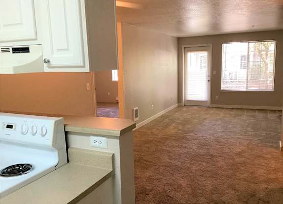 A kitchen with a white stove and white cabinets.