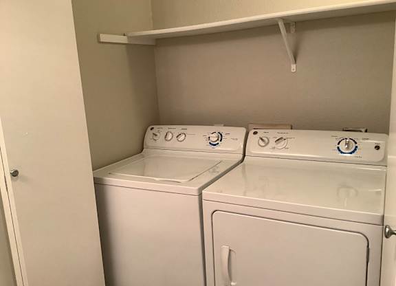 Two white washing machines in a small laundry room.