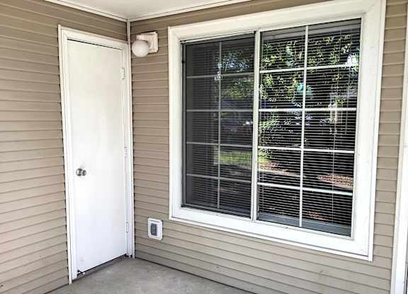 A white door is on the left and a window with blinds is on the right.