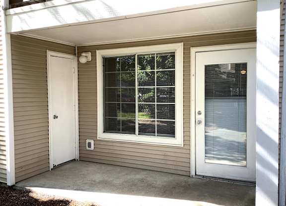A small house with a white door and a window with blinds.
