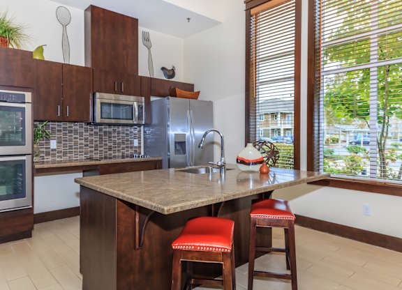 A kitchen with a brown counter top and red bar stools.