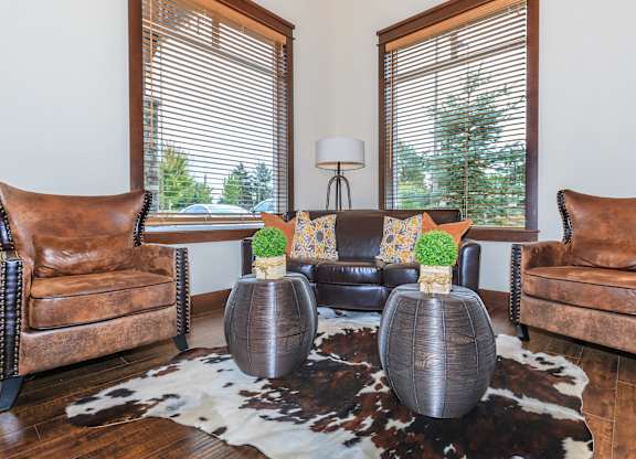 A living room with brown leather chairs and a cowhide rug.