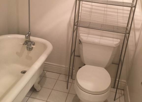 A white toilet sits next to a white bathtub in a bathroom.