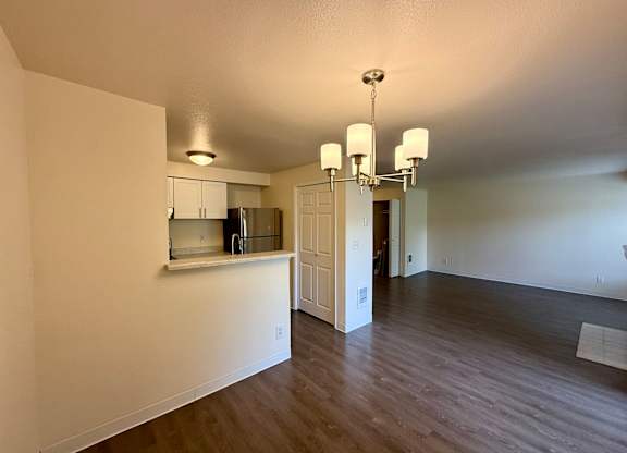 A kitchen area with a refrigerator, cabinets, and a chandelier.