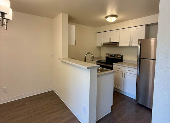 A kitchen with white cabinets and a stainless steel refrigerator.