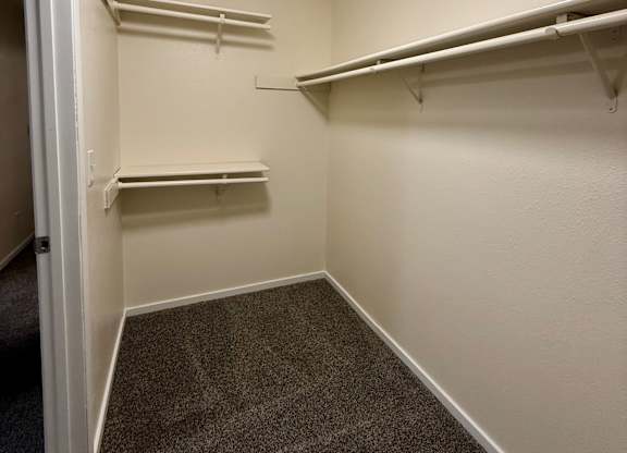 A small, empty room with a round ceiling light and grey carpet.