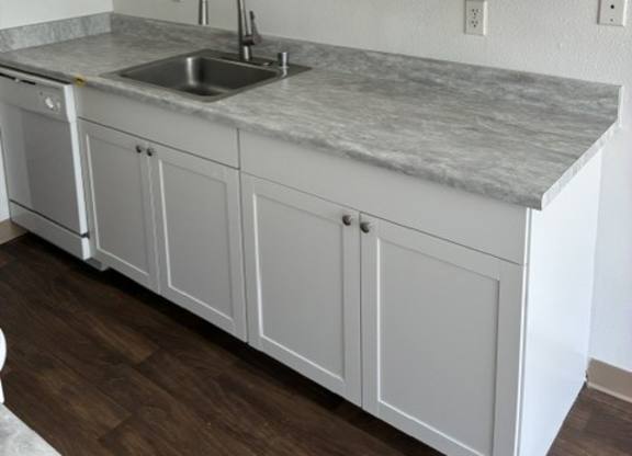 A kitchen with white cabinets and a marble countertop.