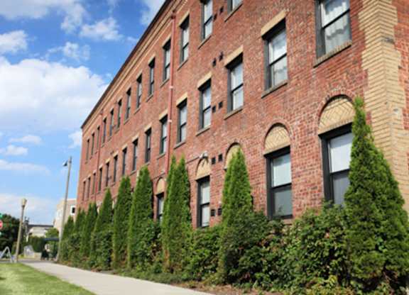 A red brick building with green trees in front.