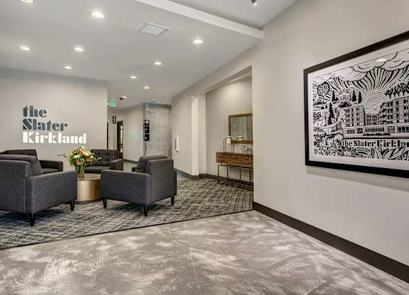 A waiting area with chairs and a large artwork on the wall.