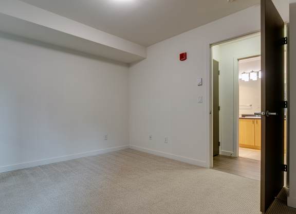 A room with a white wall and a red fire alarm.