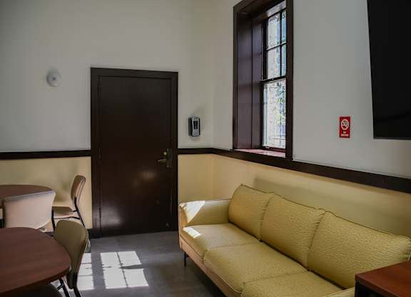 A yellow couch sits in a room with a brown door.