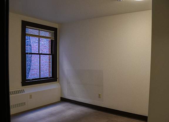 A room with a window and a radiator on the floor.