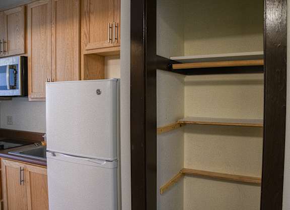 A white refrigerator stands in a kitchen next to a wall.