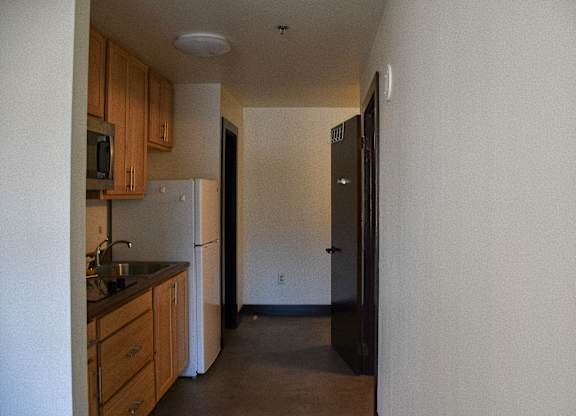 A kitchen with a sink, refrigerator, and cabinets.