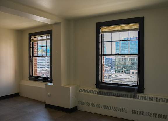 Two windows in a room with a view of the city.