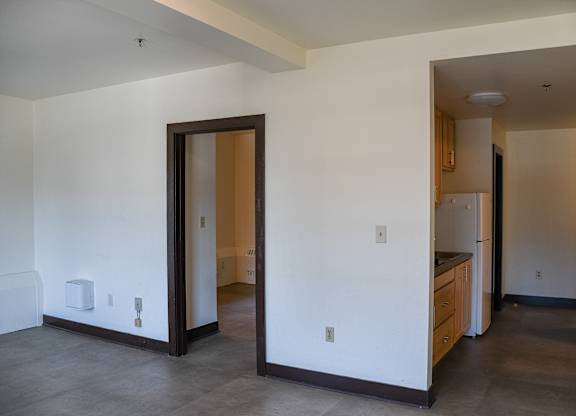 A kitchen area with a refrigerator, sink, and cabinets.