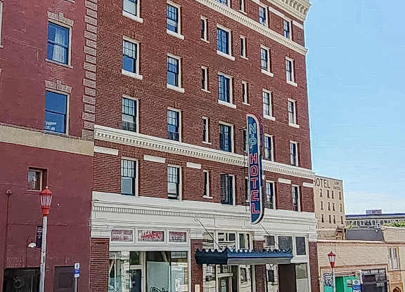 A tall red brick building with a sign that says "HOTEL" on the front.