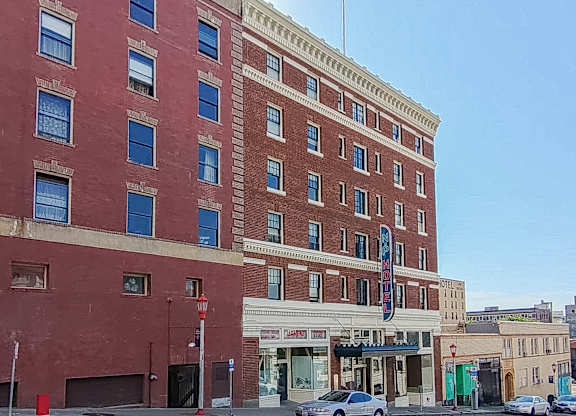 A red brick building with a blue awning sits on a street corner.