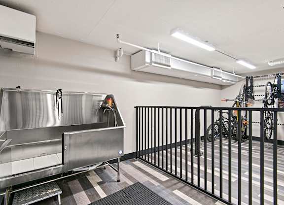 A large stainless steel sink in a room with a black fence.