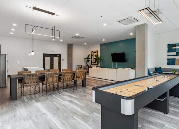 A pool table is in the middle of a room with a bar and chairs.