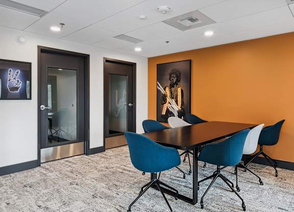 A conference room with a table and chairs and a painting on the wall.