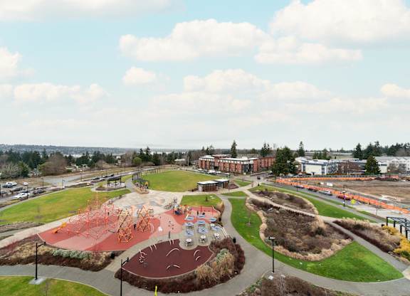 A playground with a red slide and a green hill.