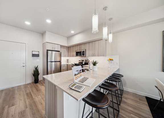 A kitchen with a bar area and a laptop on the counter.
