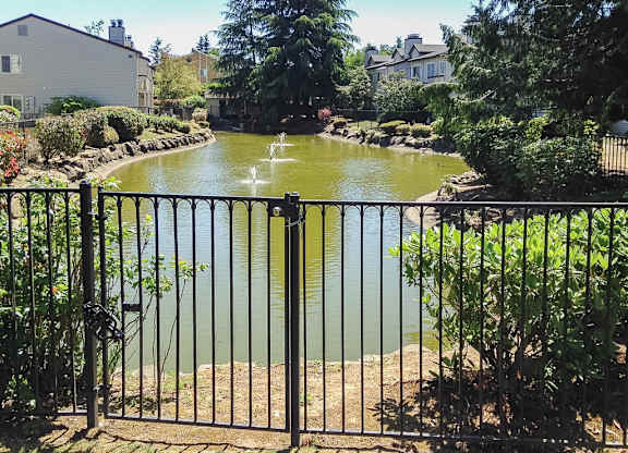 A fenced garden with a pond and water fountains.