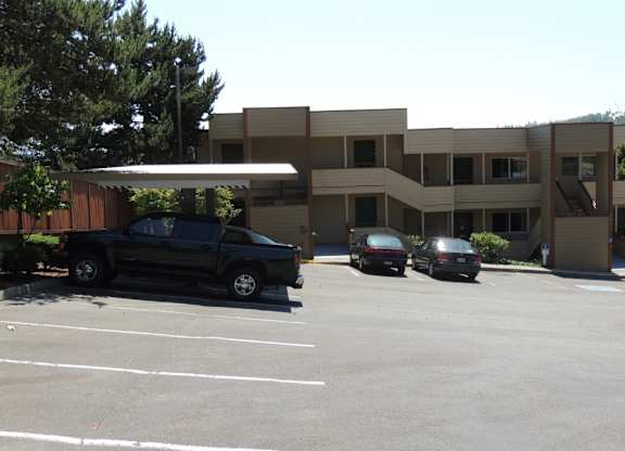 A black truck is parked in a parking lot in front of a building.