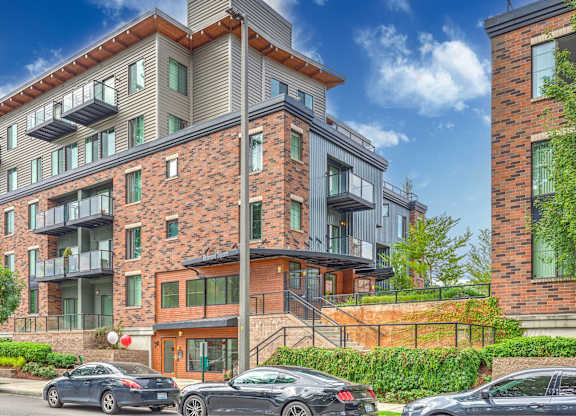 A modern apartment building with cars parked in front.