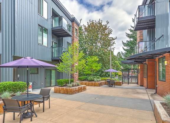 A patio with a table and chairs is surrounded by apartment buildings.
