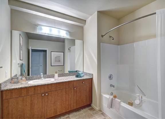 A bathroom with a white tub and a wooden vanity.