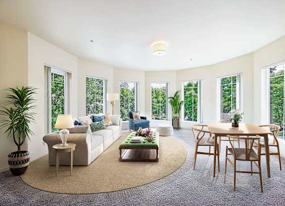 A living room with a white couch, a coffee table, and a large window.