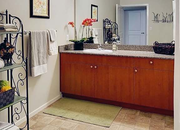 A bathroom with a brown cabinet and a mirror above it.