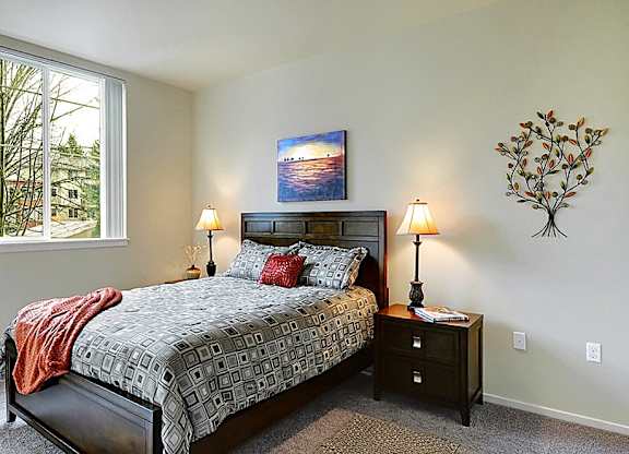 A bedroom with a large bed and a painting on the wall.