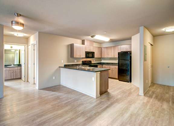 A kitchen with a black fridge and a wooden island.