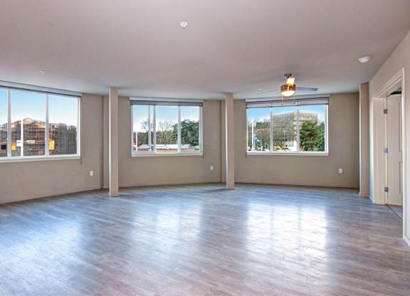 A large empty room with wooden floors and windows.