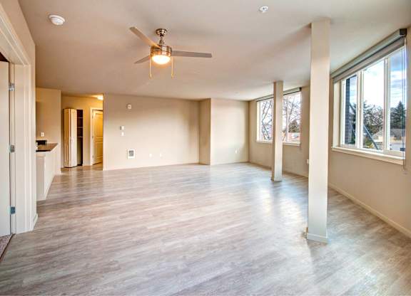 A spacious room with a ceiling fan and wooden flooring.