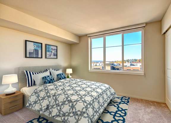 A bedroom with a large bed and a window overlooking a cityscape.