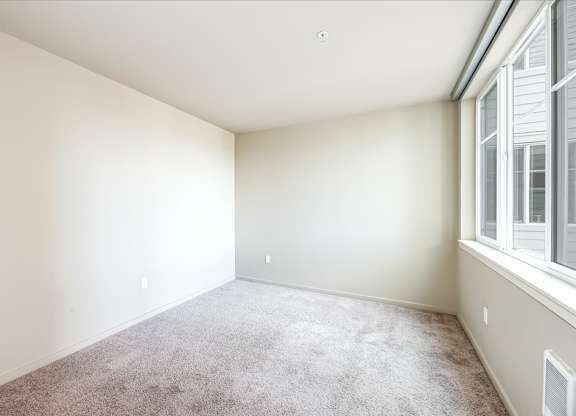 A room with a carpeted floor and a window on the right side.