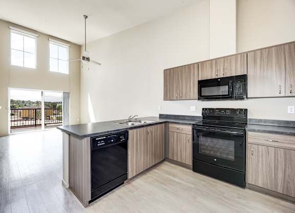 A kitchen with a black oven and wooden cabinets.
