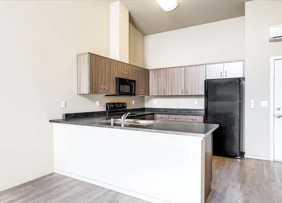 A kitchen with a black refrigerator and white countertops.