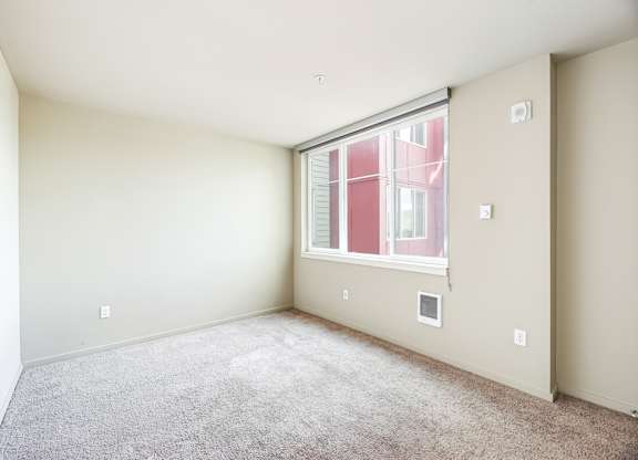 A room with a window and a carpeted floor.